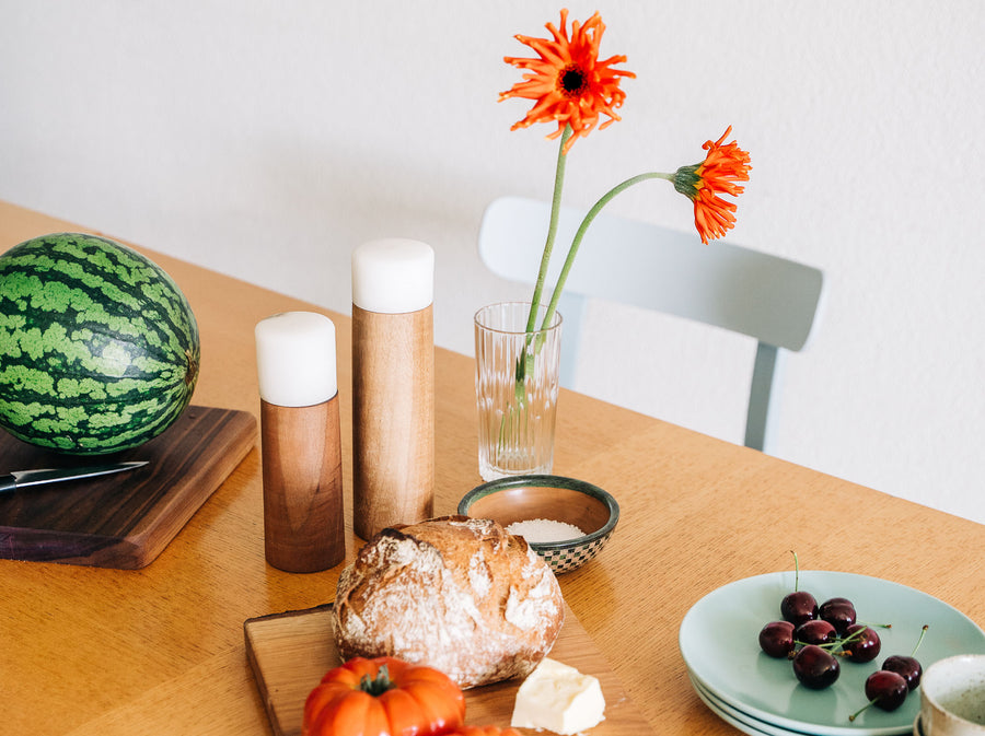 pan mobili, handgedrechselte Produkte, Salz- und Pfeffermühlen auf einem gedeckten Esstisch mit Brot und Melone
